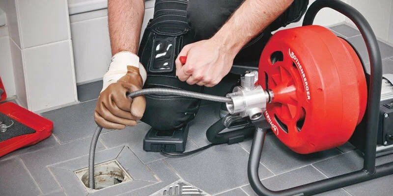 Plumber using a drain-cleaning machine in Lake Elsinore
